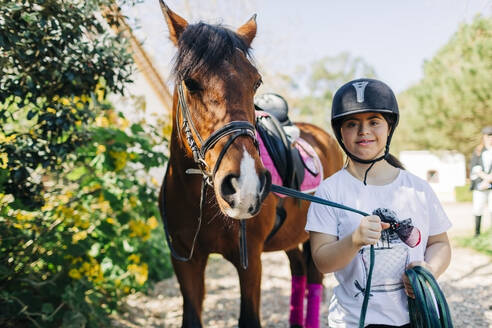 Teenager mit Down-Syndrom kümmert sich um das Pferd und bereitet es zum Reiten vor - DCRF00138