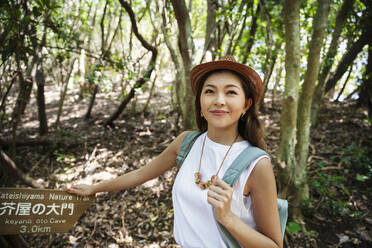 Japanese woman wearing hat hiking in a forest. - MINF14101