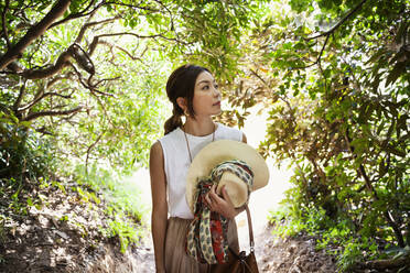 Japanische Frau mit Hut beim Wandern in einem Wald. - MINF14104