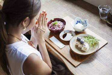 Blick von oben auf eine japanische Frau, die an einem Tisch in einem japanischen Restaurant sitzt und isst. - MINF14144