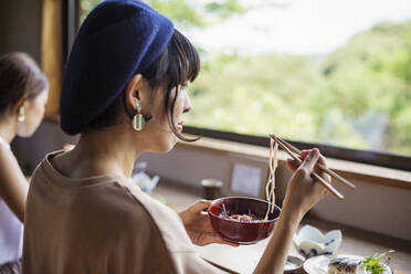 Zwei japanische Frauen sitzen an einem Tisch in einem japanischen Restaurant und essen. - MINF14148