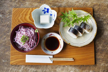 Nahaufnahme von Sushi, Tofu, Nudeln und Sojasauce auf einem Tisch in einem japanischen Restaurant. - MINF14151