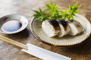 Nahaufnahme eines Tellers mit Sushi und einer Schüssel mit Sojasauce auf einem Tisch in einem japanischen Restaurant. - MINF14153