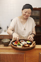Japanerin bei der Zubereitung von frischem Gemüse in einem vegetarischen Café. - MINF14176