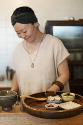 Japanerin bei der Zubereitung von frischem Gemüse in einem vegetarischen Café. - MINF14207