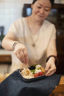 Japanerin bei der Zubereitung von frischem Gemüse in einem vegetarischen Café. - MINF14209