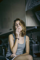 Junge Frau raucht Zigarette zu Hause - EYF00051
