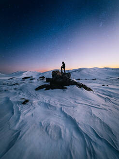 Silhouette Mann stehend auf einem Felsen auf schneebedeckten Bergen gegen den Himmel - EYF00104