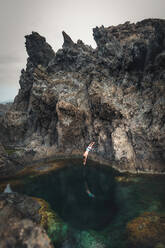 Full Length Of Man Jumping In Pond From Rocky Mountain - EYF00111