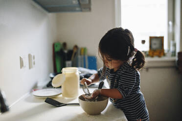 Side View Of Girl Preparing Food On Kitchen Counter At Home - EYF00134