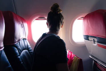 Frau schaut durch das Fenster, während sie im Flugzeug reist - EYF00143