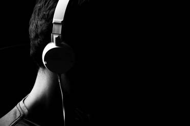 Side View Of Man Wearing Headphones Against Black Background - EYF00204