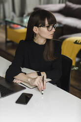 Thoughtful Businesswoman With Laptop Sitting At Office Desk - EYF00360