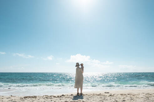 Volle Länge der Frau hält Baby, während stehend am Strand gegen den Himmel - EYF00377