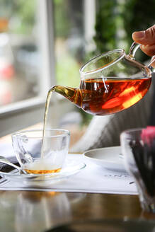 Nahaufnahme von Hand gießen Tee in Glas - EYF00435