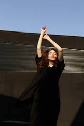 Woman With Arms Raised Standing Against Wall - EYF00493