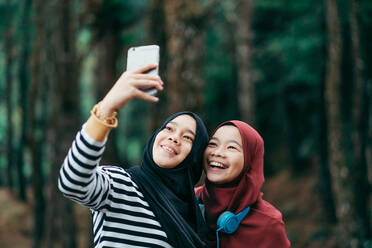 Teenager-Mädchen mit Freund, der ein Selfie vom Mobiltelefon macht - EYF00518