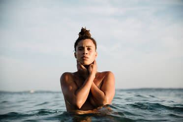 Porträt einer jungen Frau ohne Hemd, die im Meer gegen den Himmel schwimmt - EYF00553