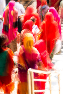 Brightly coloured saris (clothing) and veils, blurred in motion for effect, worn by women walking down towards the sacred lake, Pushkar, Rajasthan, India, Asia - RHPLF13918