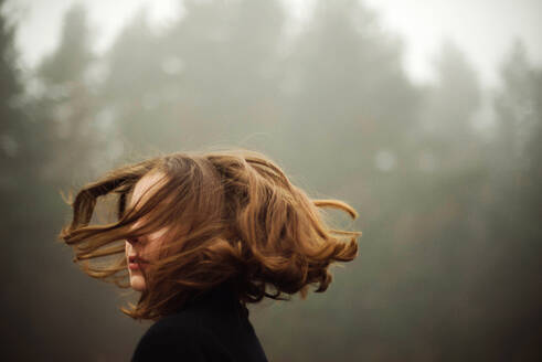 Frau steht bei nebligem Wetter im Wald - CAVF77069