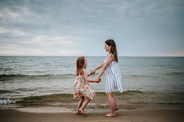 Seitenansicht von Schwestern tanzen am Strand am See Michigan - CAVF77072