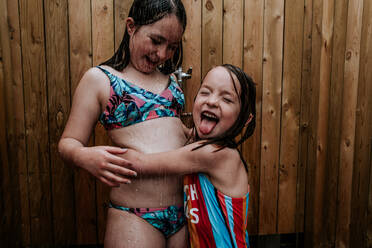 Schwestern spielen im Freien Dusche an einem Sommertag - CAVF77073