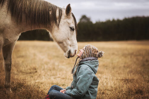 Pferd und Mädchen schauen sich auf einem Feld im Herbst an - CAVF77128