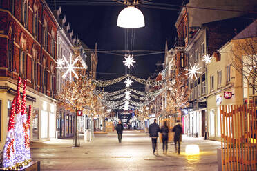 Blur Image Of People Walking On Street Amidst Illuminated Buildings Decorated With Christmas Lights - EYF00643