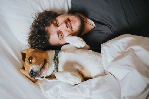 High Angle Portrait von Mann mit Hund auf dem Bett zu Hause - EYF00723