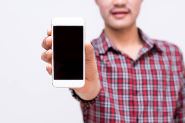 Midsection Of Young Man Showing Mobile Phone While Standing Against White Background - EYF00734