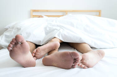 Low Section Of Couple Sleeping On Bed At Home - EYF00818