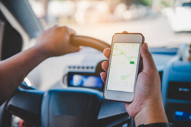 Abgeschnittene Hand mit Global Positioning System im Mobiltelefon beim Autofahren - EYF00858