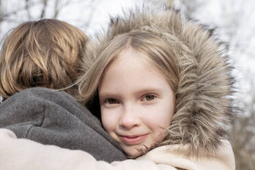 Nahaufnahme eines lächelnden Mädchens, das seinen Vater an einem sonnigen Tag umarmt, Tarusa, Russland - EYAF00956