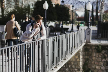 Mann auf einer Brücke beim Telefonieren - LJF01397