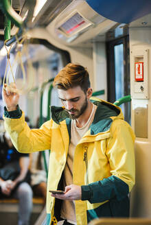 Mann benutzt Mobiltelefon in der U-Bahn - LJF01409