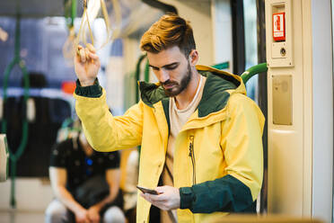 Mann benutzt Mobiltelefon in der U-Bahn - LJF01410