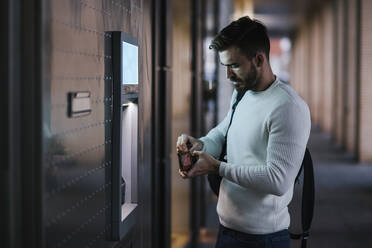 Mann beim Geldabheben an einem Geldautomaten in der Stadt - LJF01425