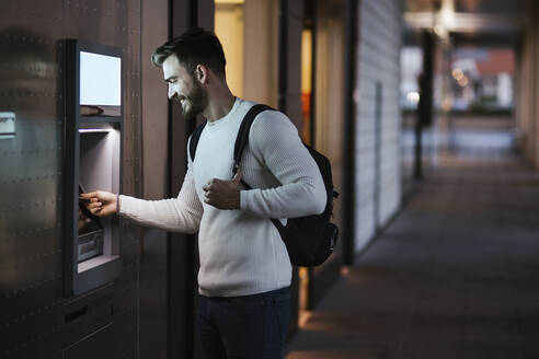 Mann beim Geldabheben an einem Geldautomaten in der Stadt - LJF01428