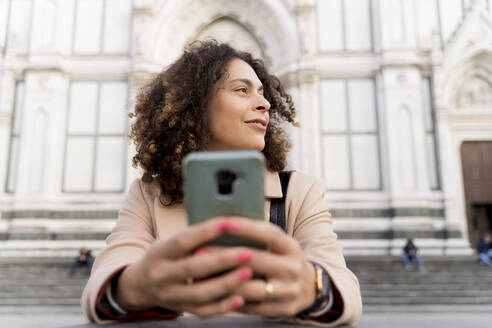 Frau mit Smartphone in der Kirche Santa Croce, Florenz, Italien - FMOF00906