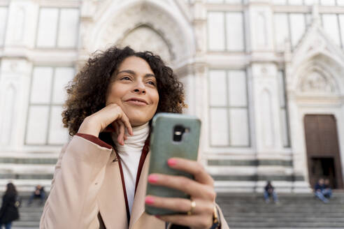 Frau mit Smartphone in der Kirche Santa Croce, Florenz, Italien - FMOF00907