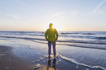 Rückansicht in voller Länge eines älteren Mannes, der während des Sonnenuntergangs am Strand steht, Nordseeküste, Flandern, Belgien - GWF06542