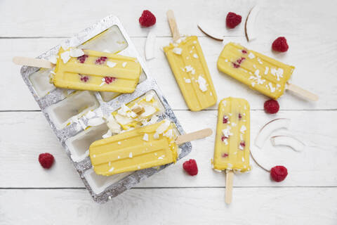 Homemade mango and raspberry popsicles with coconut chips stock photo