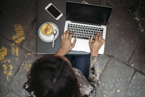 Draufsicht auf eine junge Frau, die einen Laptop in einem Straßencafé benutzt - JPIF00451