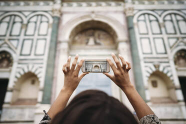 Nahaufnahme einer jungen Frau, die ein Smartphone-Foto in der Stadt macht, Florenz, Italien - JPIF00469