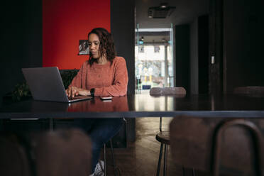 Young woman using laptop in a cafe - JPIF00479