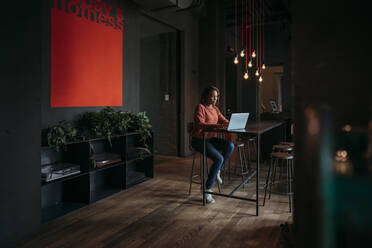 Junge Frau mit Laptop in einem Café - JPIF00481