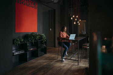 Young woman using laptop in a cafe - JPIF00481