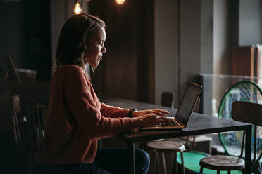 Junge Frau mit Laptop in einem Café - JPIF00485