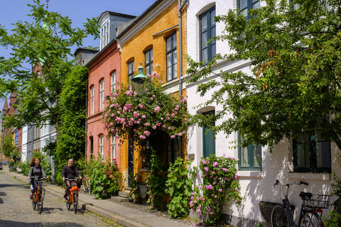 Dänemark, Kopenhagen, Mann und Frau auf Fahrrädern in der Straße des historischen Stadtteils Nyboder, lizenzfreies Stockfoto
