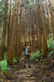 Mann steht in einem von Bäumen umgebenen Wald, Insel Sao Miguel, Azoren, Portugal - AFVF05671